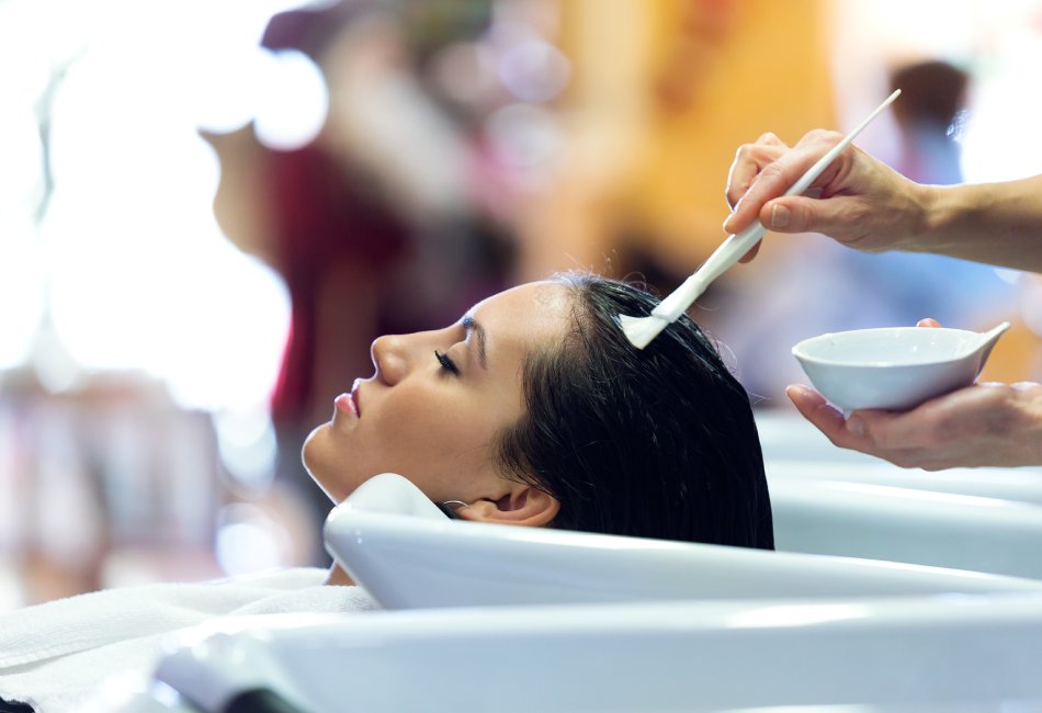 Centro de Peluquería y Estética Gina Bort, especialistas en Tratamiento Reparador y Anti-Encrespado de Pelo con Manteca de Karité en Benicàssim. Peluquera aplicando el tratamiento a la clienta.